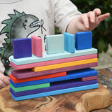 Child's hands stacking the colorful Glückskäfer building slats on a wooden surface outdoors.