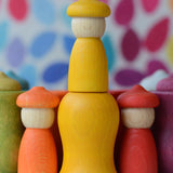 Handcrafted yellow Grapat wooden peg doll standing on a matching curved cup from the 7 moons weekly calendar set