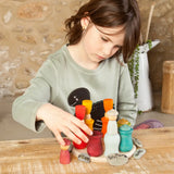 Child balancing coloured wooden peg dolls inside the matching cups from the Grapat handcrafted wooden 7 moons weekly calendar set