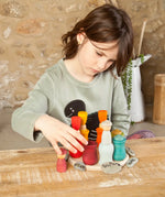 Child balancing coloured wooden peg dolls inside the matching cups from the Grapat handcrafted wooden 7 moons weekly calendar set