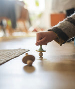 A child is playing with the wooden spinning tops from the Grapat Advent Calendar 2024