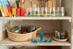 A close up of the Grapat mis match bloom set showing the blue wooden geometric pieces stacked on top of each other on a shelf with additional pieces in jars on another shelf