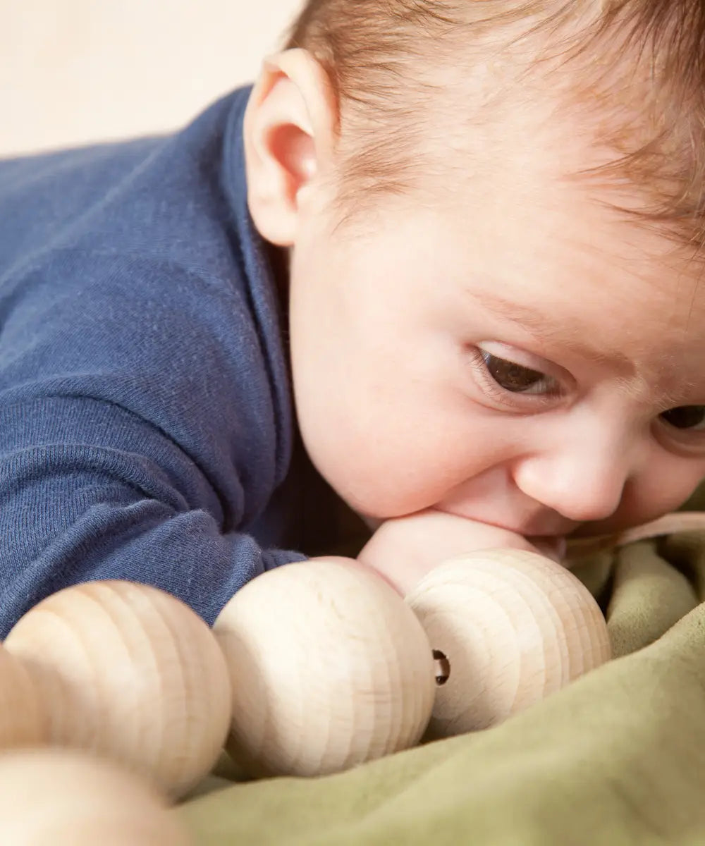 Baby with the Grapat natural wooden sensory ball garland in the mouth