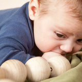 Baby with the Grapat natural wooden sensory ball garland in the mouth
