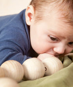 Baby with the Grapat natural wooden sensory ball garland in the mouth