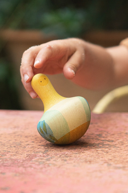 Child's hand holding a wooden yellow and blue chunky wobbly bird by Grapat to represent new Grapat at Babipur, official UK stockist.