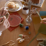 Grapat Handmade and handpainted Wooden winter sparkle decorations available at Babipur on a wooden table with 2 children making festive crafts.