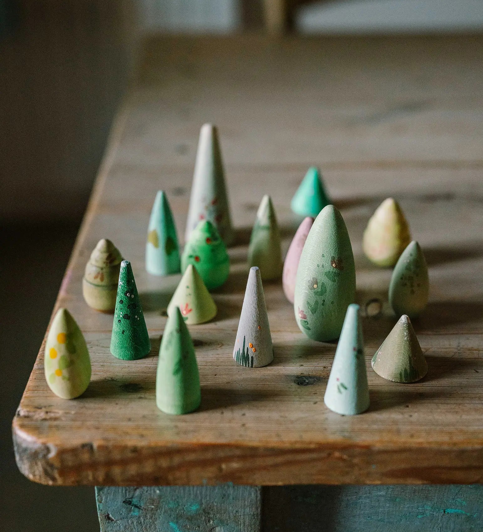 Grapat's handcrafted wooden green forest tree set pieces standing on a table showing the hand painted flower detail 