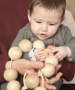 Baby holding the Grapat natural wooden sensory ball garland