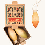 A opened natural cardboard box with the wooden Grapat glow lamps inside on a cream background.