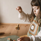 A child holding a wooden and hand painted decoration made from wooden pieces from the Grapat 2025 advent calendar available at Babipur