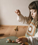 A child holding a wooden and hand painted decoration made from wooden pieces from the Grapat 2025 advent calendar available at Babipur