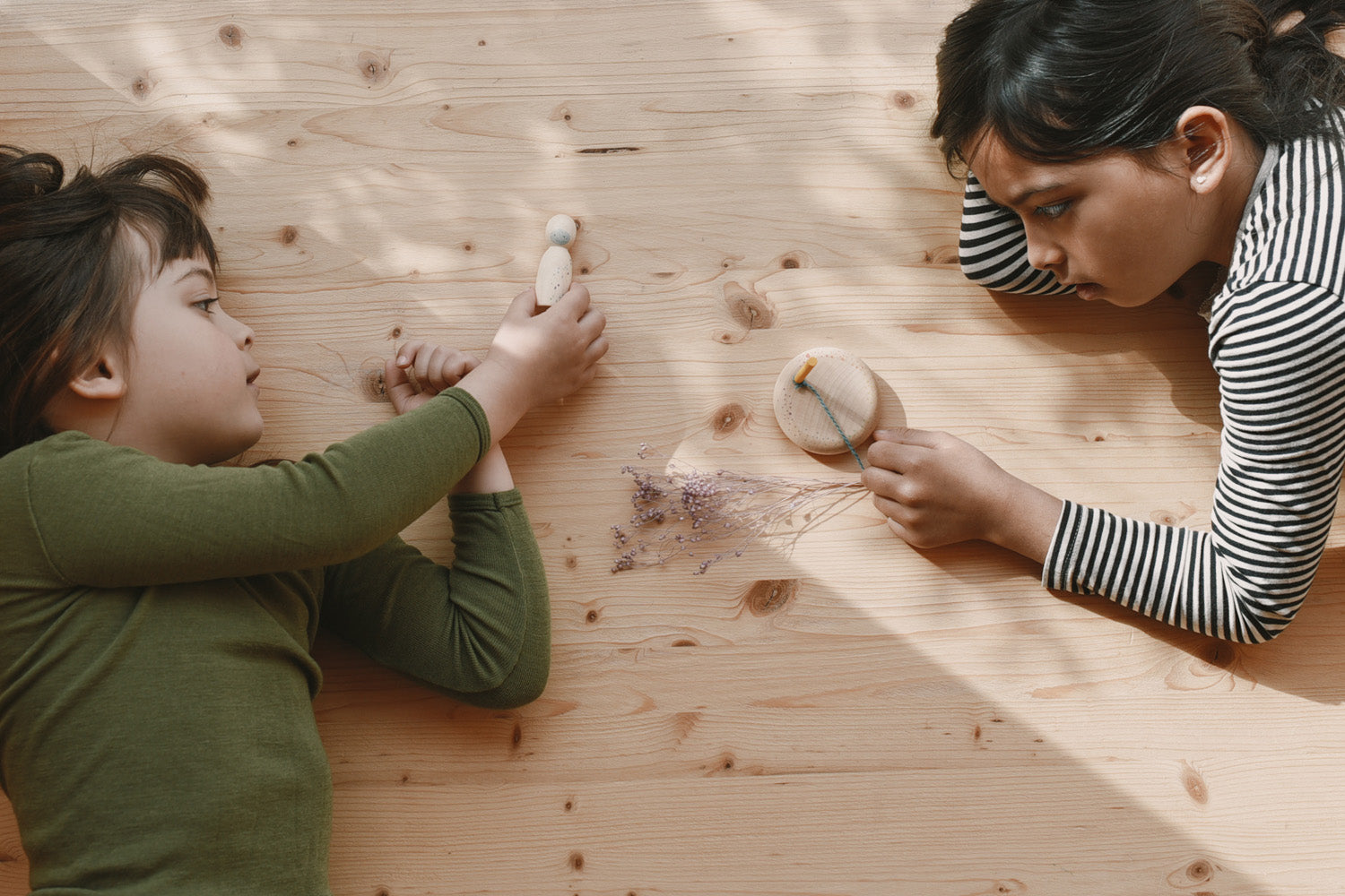 2 children playing with different handmade and hand painted wooden pieces from the Grapat 2025 advent calendar available at Babipur.
