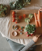 A top down view of a table with different veg and some of the handmade and hand painted wooden veg pieces from the Grapat advent 2025 calendar available at Babipur.