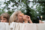 2 children standing behind a washing line outside in the garden holding a orange fox puppet next to the eyes.