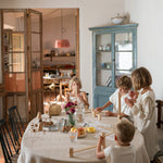 Children sitting next to a dining table stacking the different wooden tubes and planks from the Grapat woodland set. 