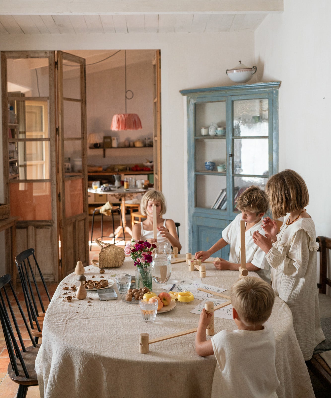 Children sitting next to a dining table stacking the different wooden tubes and planks from the Grapat woodland set. 