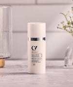 The Green People Age Defy+ Daily SPF30 Moisturiser is stood on a white and grey marble table on a white tile background