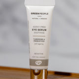 The Green People, natural and organic soothing eye serum is stood on a small wooden table with a grey background