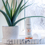 Green People glow & protect spf30 150ml cream bottle standing on a stone dish in a bathroom next to a aloe vera plant 