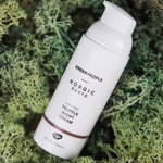 The Green People Nordic Roots Truffle Night Cream - 50ml is laid on a mossy green background 