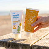 Green People and organic children SPF50 water repellent scent free 150ml sun cream standing on a wooden table
