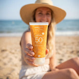 Adult holding a tube of Green People SPF50 water repellent sun cream s
at the beach