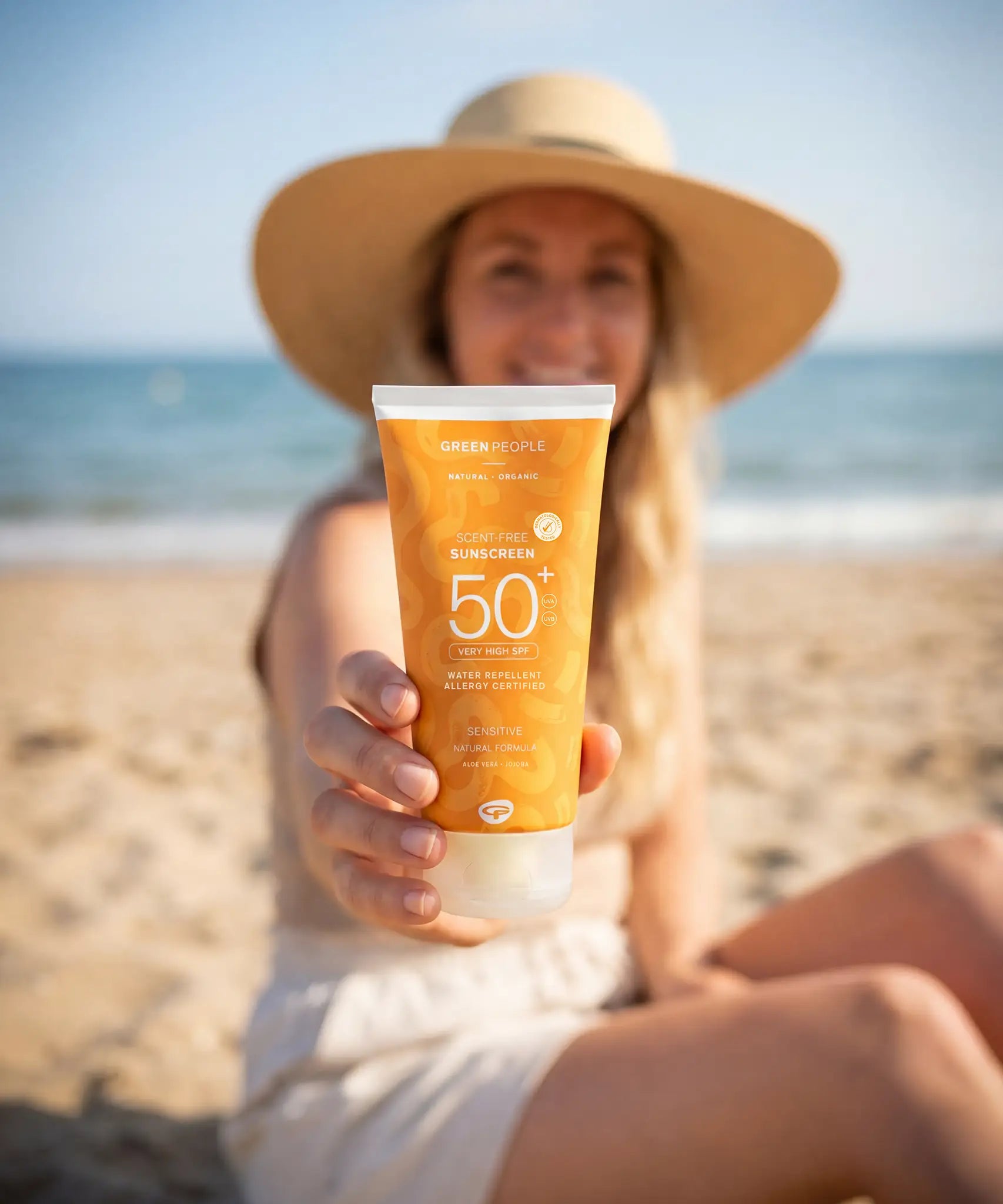 Adult holding a tube of Green People SPF50 water repellent sun cream s
at the beach