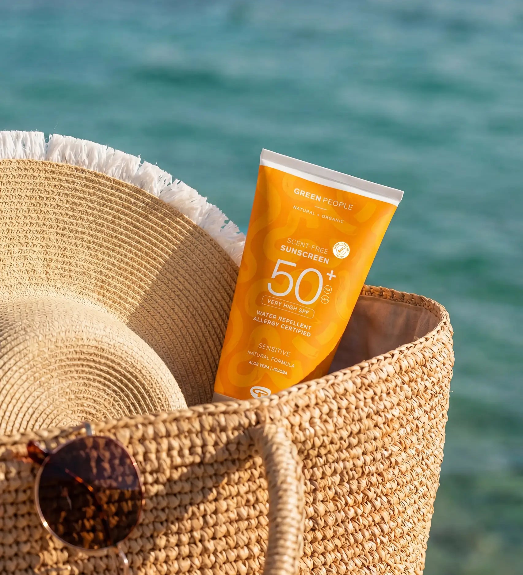 Green People SPF50 water repellent sun cream inside a basket by the sea