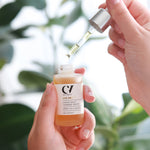 A person using the dropper and holding the bottle of the Green People Age Defy+ Liquid Gold Tanning Drops 30ml