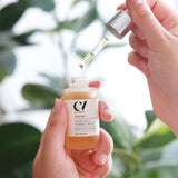 A person using the dropper and holding the bottle of the Green People Age Defy+ Liquid Gold Tanning Drops 30ml