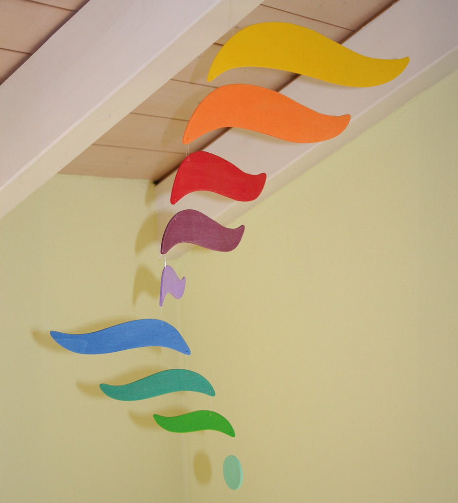 A close up of the Grimms wooden harmony mobile available at Babipur. Showing the different coloured wings in motion and hanging under a ceiling