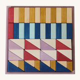Grimm's wooden rhythm building set in a purple square frame shows handcrafted pieces in different colours