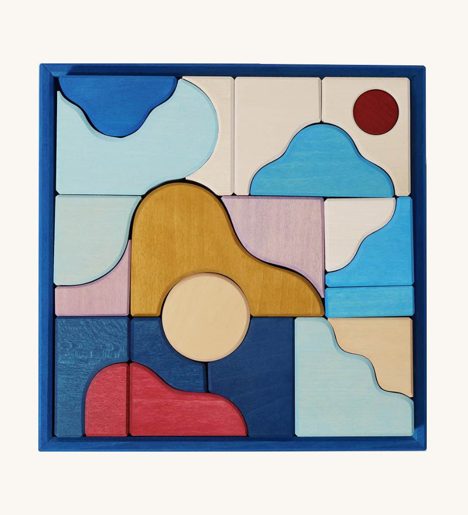 Grimm's wooden wave building set in a blue square frame shows handcrafted pieces in different colours