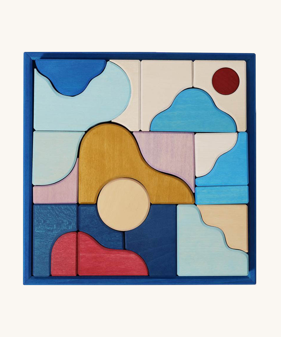 Grimm's wooden wave building set in a blue square frame shows handcrafted pieces in different colours