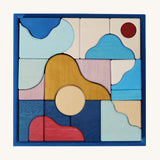 Grimm's wooden wave building set in a blue square frame shows handcrafted pieces in different colours