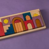 Grimm's wooden panorama building set in a rectangle frame lying flat on a purple surface.