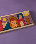 Grimm's wooden panorama building set in a rectangle frame lying flat on a purple surface.