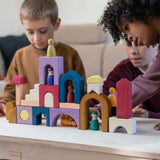 Children playing with the Grimm's wooden panorama building set on a wooden table in a living room setting
