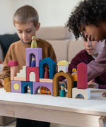 Children playing with the Grimm's wooden panorama building set on a wooden table in a living room setting
