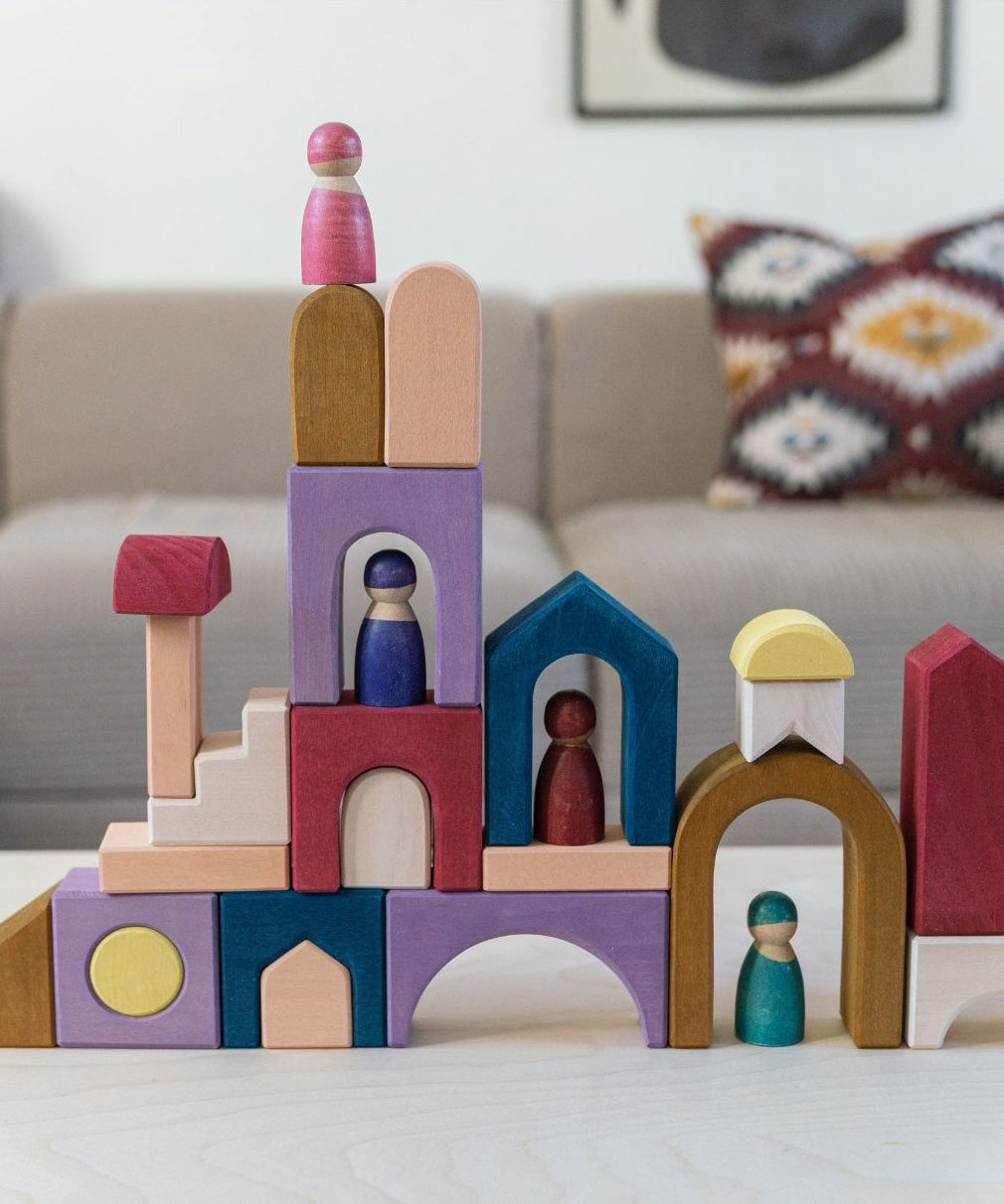Grimm's wooden panorama building set on a wooden table in a living room setting. Shows pieces stacked on top of eachother 