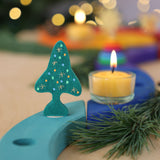 A Grimm's Christmas Tree Celebration Ring Decoration figure available at Babipur inserted into a light blue celebration piece in a festive inspired display. 