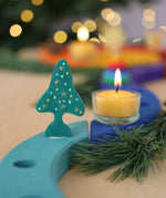 A Grimm's Christmas Tree Celebration Ring Decoration figure available at Babipur inserted into a light blue celebration piece in a festive inspired display. 