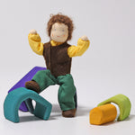Grimm's Brown Haired Man Doll - Erle has its foot resting on a wooden Grimm's block and its arms bent upward showing the flexibility of the dolls arms and legs.