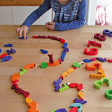 A child playing with the Grimm's Figures For Counting & Story Telling on a wooden table. 