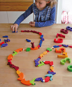 A child playing with the Grimm's Figures For Counting & Story Telling on a wooden table. 