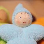 A closer look at the Grimm's Light Blue Pastel Dwarf face to show the doll's smiling face. The light blue dwarf doll has a red smile, light pink rosy cheeks, blue eyes and 4 brown painted strands of hair.