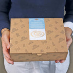 Person holding a Grimm's natural spiral celebration ring box with a product label on it.