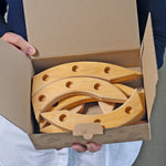 Grimm's natural spiral celebration ring pieces in a cardboard box held by a person.