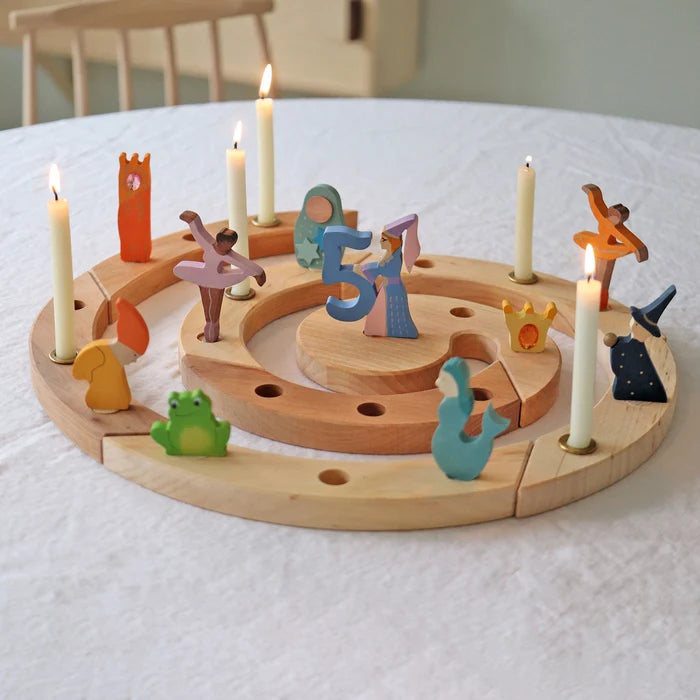 Grimm's natural spiral celebration ring with colorful figures and candles on a white surface